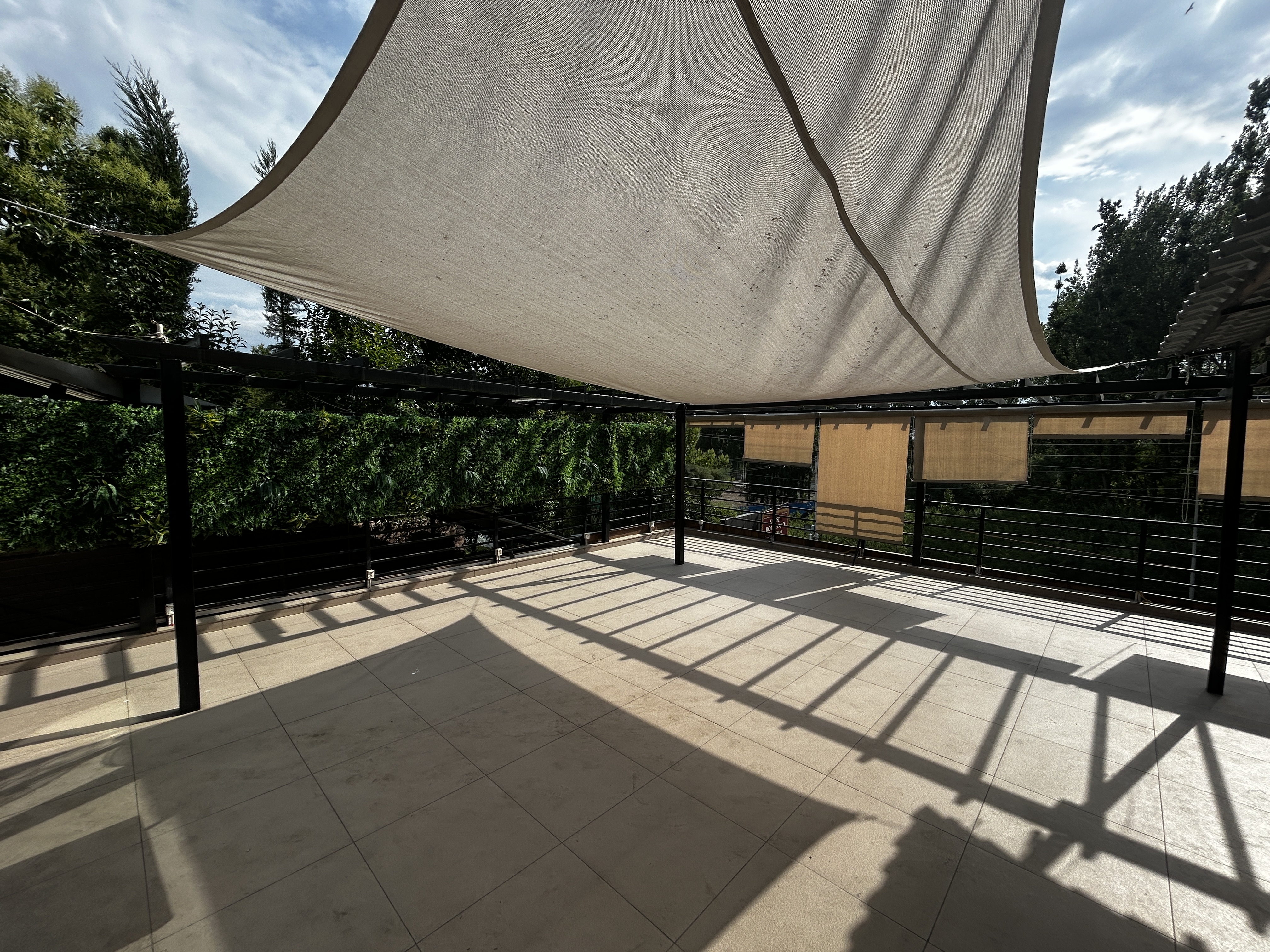 The rooftop terrace of Sunset Boulevard Restaurant - open-air pergola dining overlooking the road, trees and the Zabarwan mountains